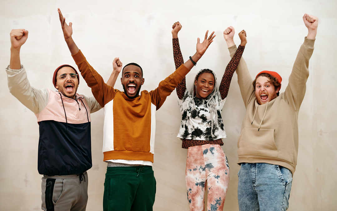 asdsdsds A diverse group of four people cheering with their arms up.